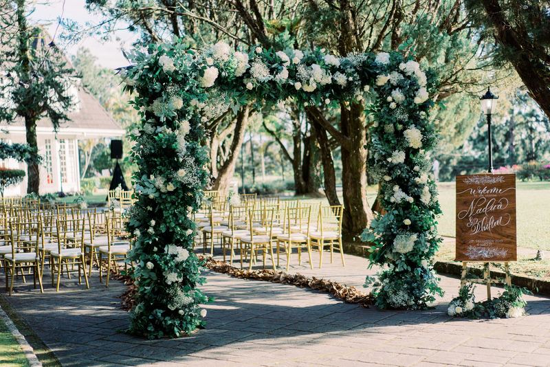 Greenery and white flower arch over the ceremony walkway