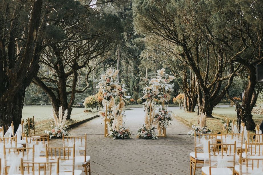 Ceremony aisle with pampas floral stands under the estate's trees